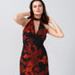 Model posing with hand near face in orange and black floral print dress, drawing attention to neckline and print.