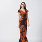 Model in front-facing pose wearing orange and brown abstract crepe dress with ruffle sleeves.