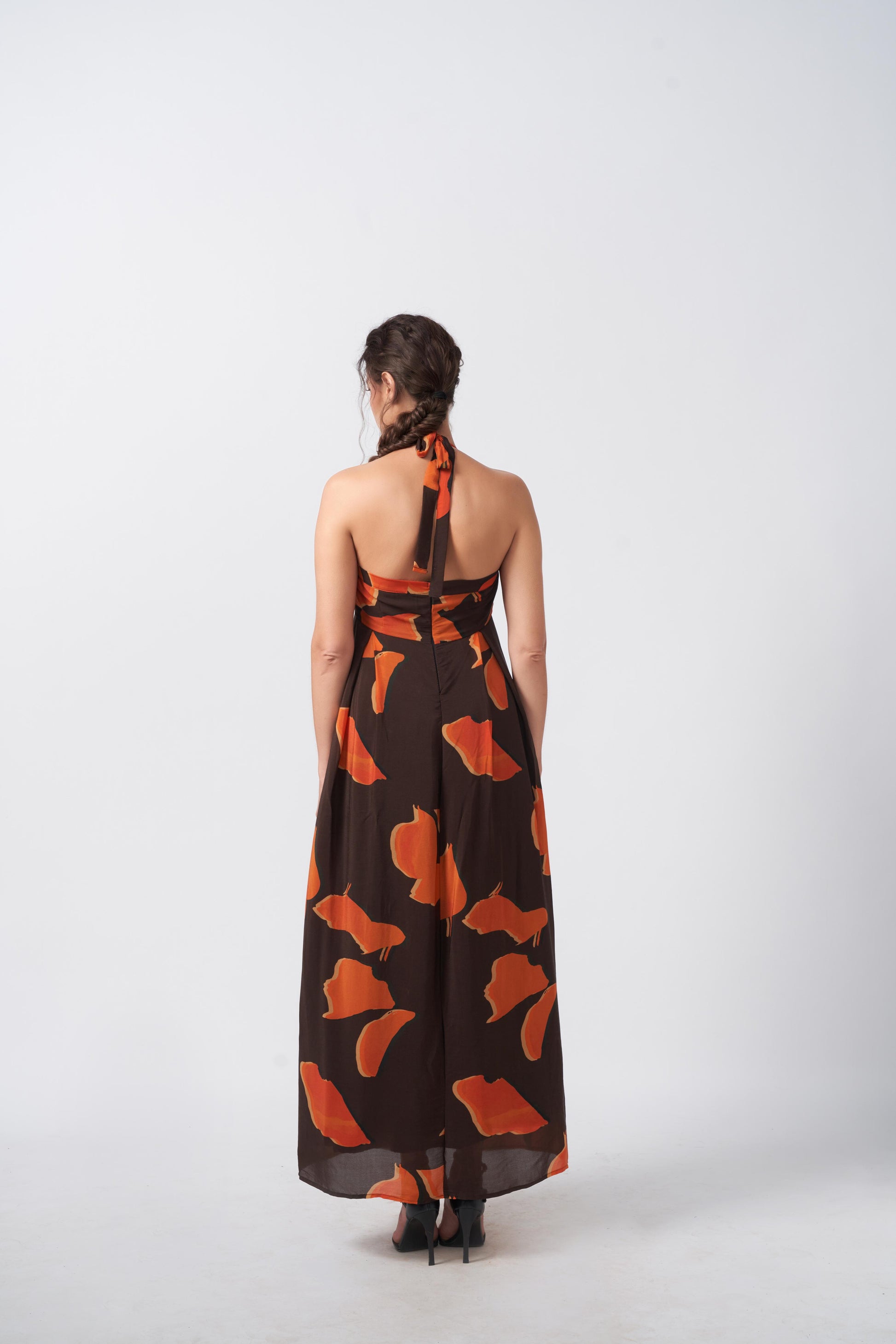 Back view of halter tie-back midi dress in vivid orange and brown print, highlighting the tie-up detail.