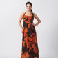 Model facing front in orange and brown abstract print halter-neck midi dress, highlighting the relaxed silhouette.