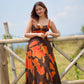 Model holding the railing with both hands in the abstract print dress, emphasizing the flow and length.