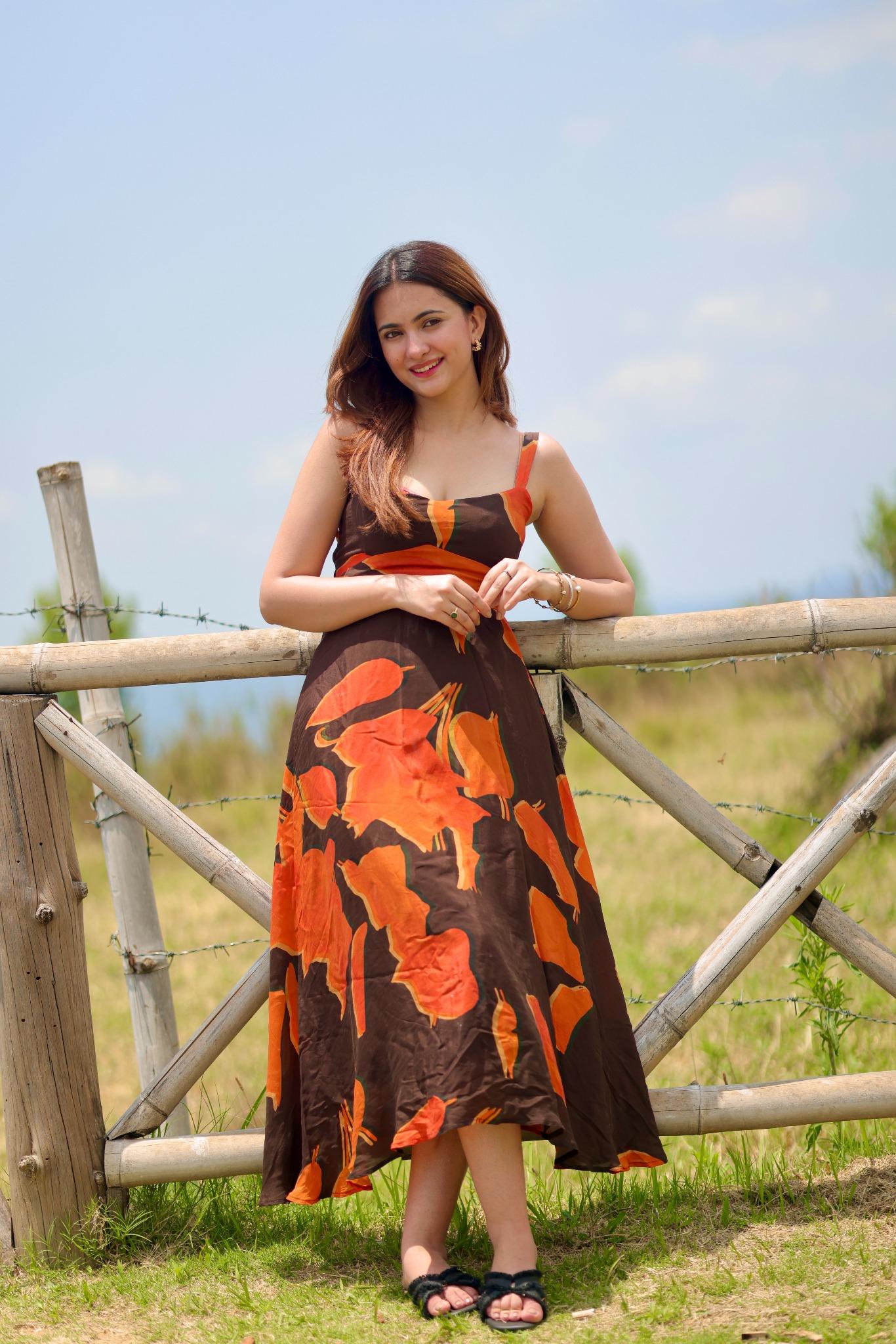 Model holding the railing with both hands in the abstract print dress, emphasizing the flow and length.
