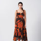 Model facing forward in orange and brown abstract print midi dress, showcasing the silhouette and square neckline.