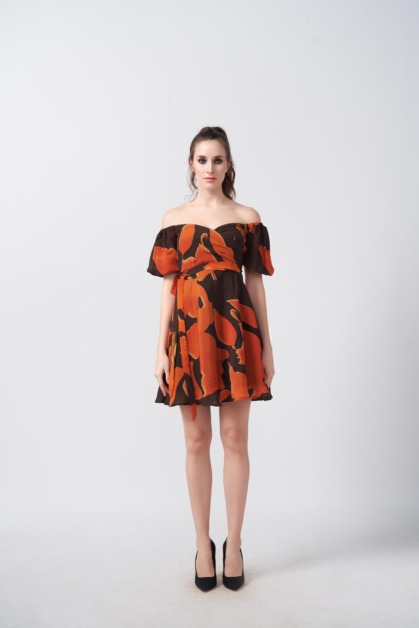 Model standing straight in vibrant puff sleeve mini dress with abstract pattern and flared hem.
