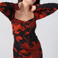  Close-up of overlapped neckline and fitted bodice in orange and black floral print.