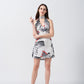 Model wearing a white and grey short silk dress with halter neck and knot front detail, standing against a plain background.