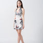 Model in side view pose wearing short silk halter dress with tie-back and floral print accented with red highlights.