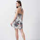 Model back view in a short white and grey floral silk dress with a halter neck and flared hemline.