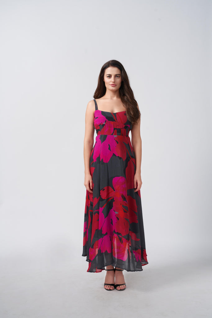 Model wearing a pink and black abstract floral midi dress with delicate straps, styled for elegant daytime occasions.
