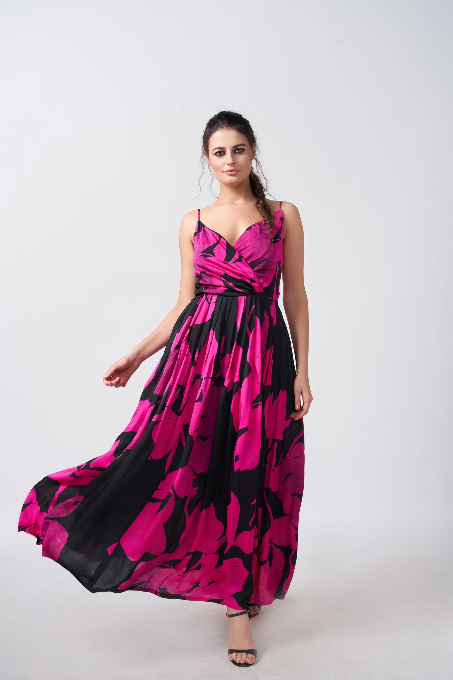 Model wearing an ankle-length satin dress with pink and black floral print, overlap neck, and spaghetti straps.