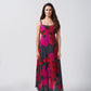 A sleeveless maxi dress showcasing a bold abstract floral print in vibrant pink and red against a charcoal background, finished with a clean, structured bodice.