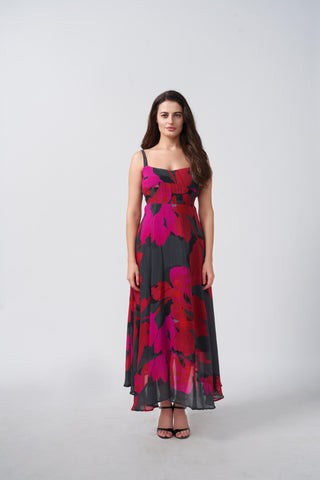A sleeveless maxi dress showcasing a bold abstract floral print in vibrant pink and red against a charcoal background, finished with a clean, structured bodice.