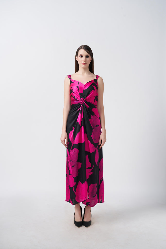Model wearing ankle-length satin dress with pink and black floral print, front knot detail, and shoulder straps.