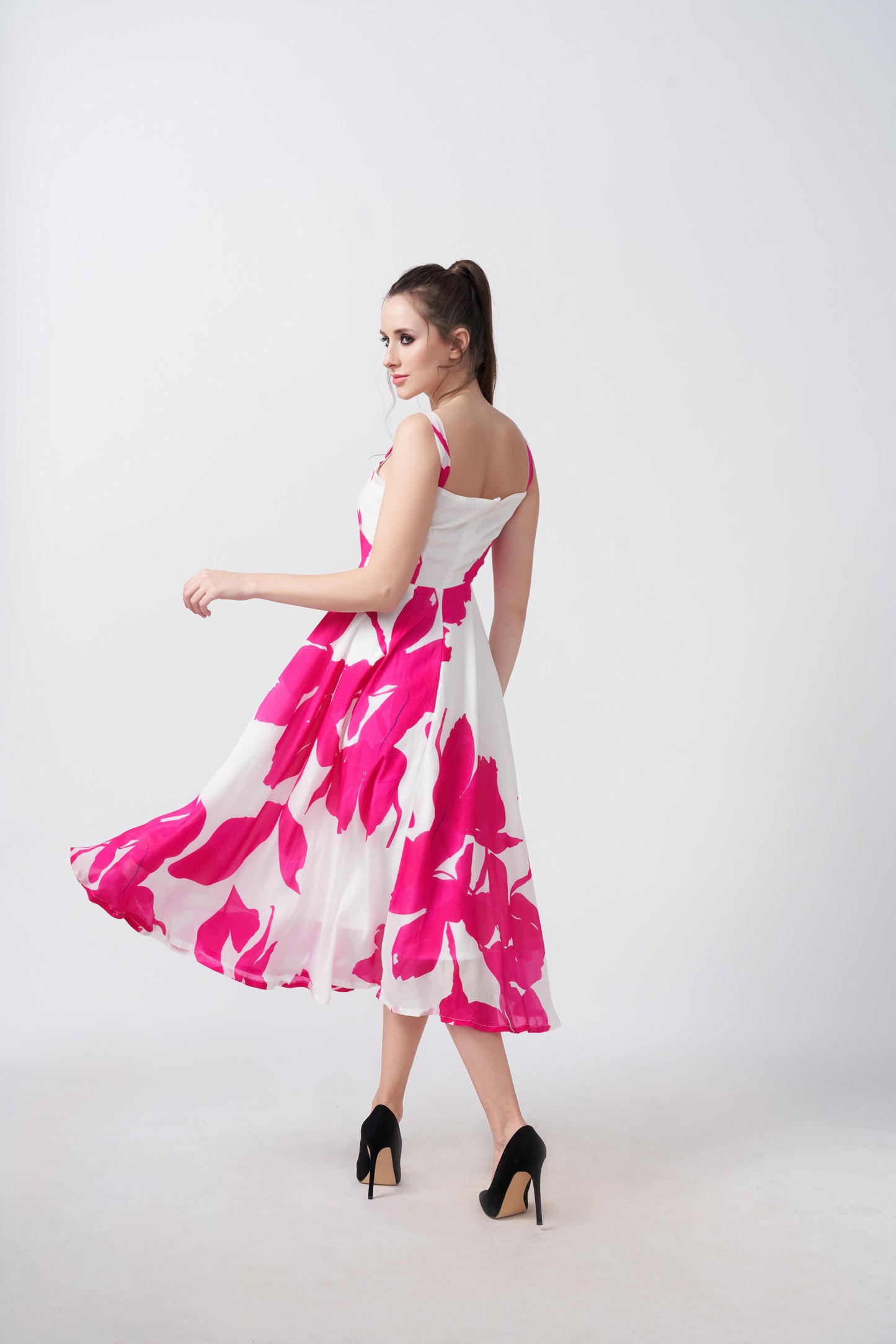 Model twirling in the pink and white floral crepe midi dress, showcasing its graceful flow and structure.