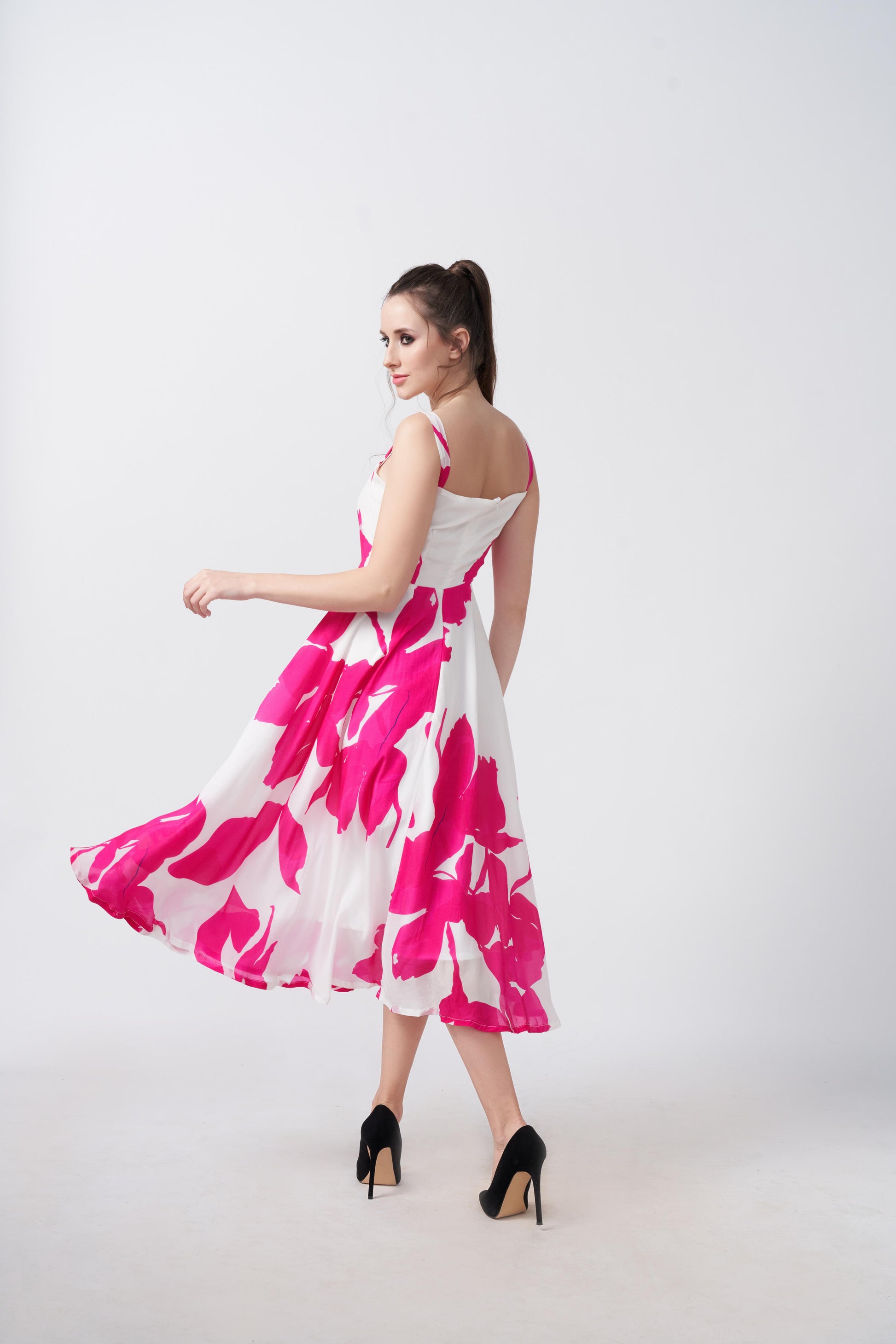 Model twirling in the pink and white floral crepe midi dress, showcasing its graceful flow and structure.