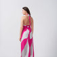 Back view of model in pink and grey halter maxi dress, featuring tie-up detail and fluid fabric fall.