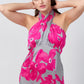 Close-up of the model adjusting halter neckline, focusing on pink floral print and detailing on satin midi dress.