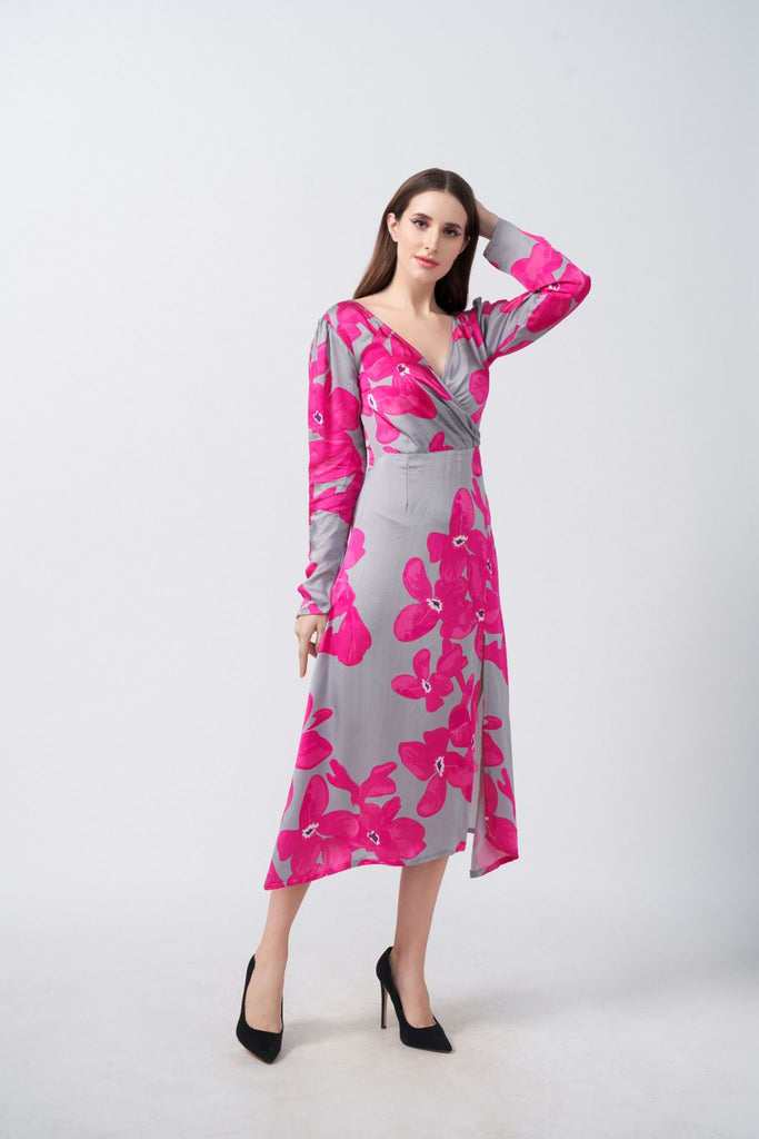Model wearing a satin midi dress with pink floral print and full-length sleeves, posing with hand in hair against a grey background.