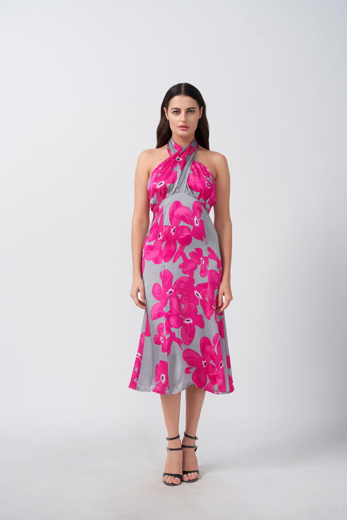 Model facing front in pink and grey floral satin midi dress with halter neck, highlighting the sleek silhouette.