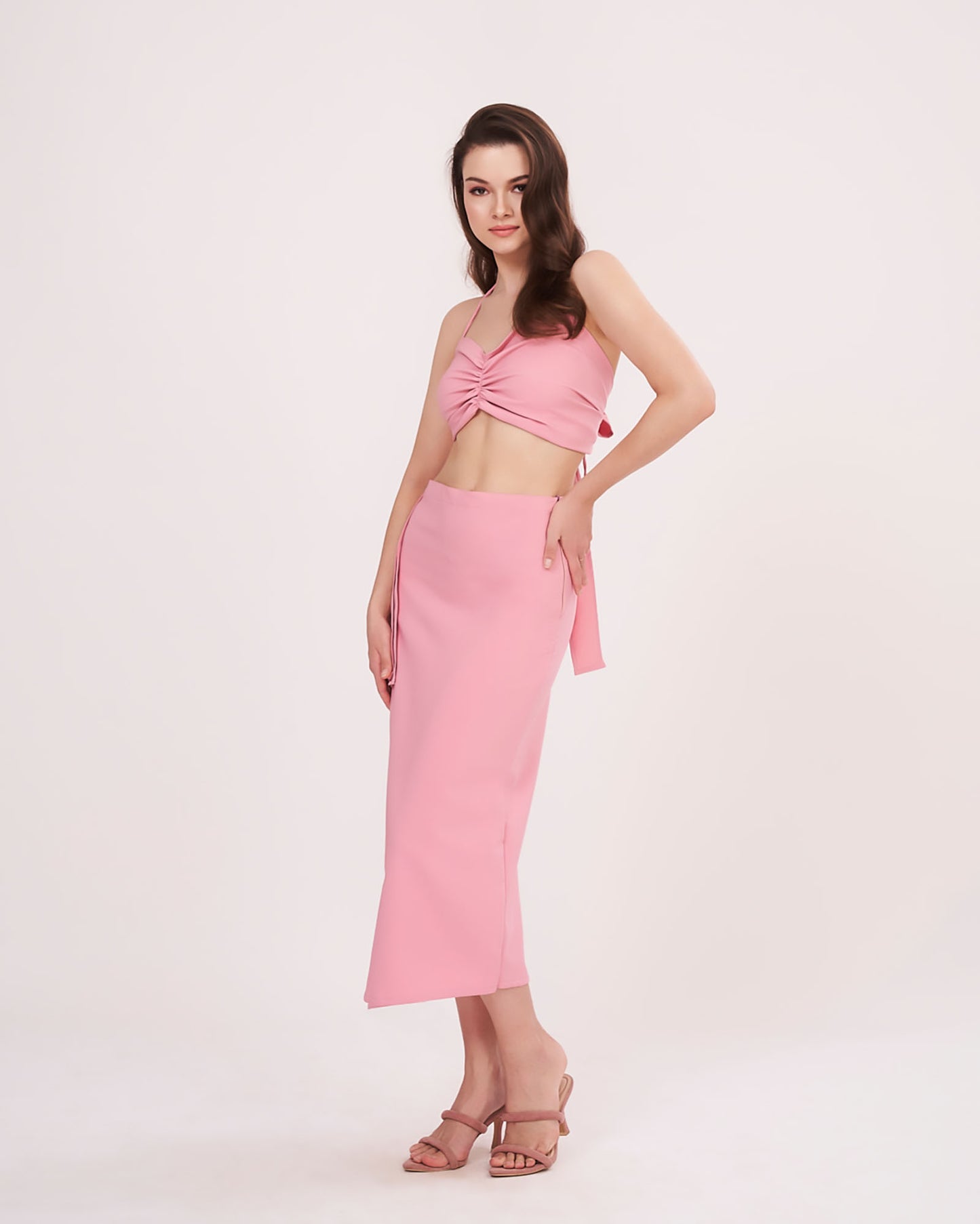 Side angle view of the pink crop top and skirt co-ord, emphasizing the ruched top and flowing frill of the skirt.