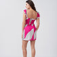 Back view of model wearing short pink and white chinon dress with frill shoulder straps and abstract design.