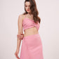 Model turned to a 3/4th profile, highlighting the ruched front and side frill flow of the solid pink co-ord skirt set.