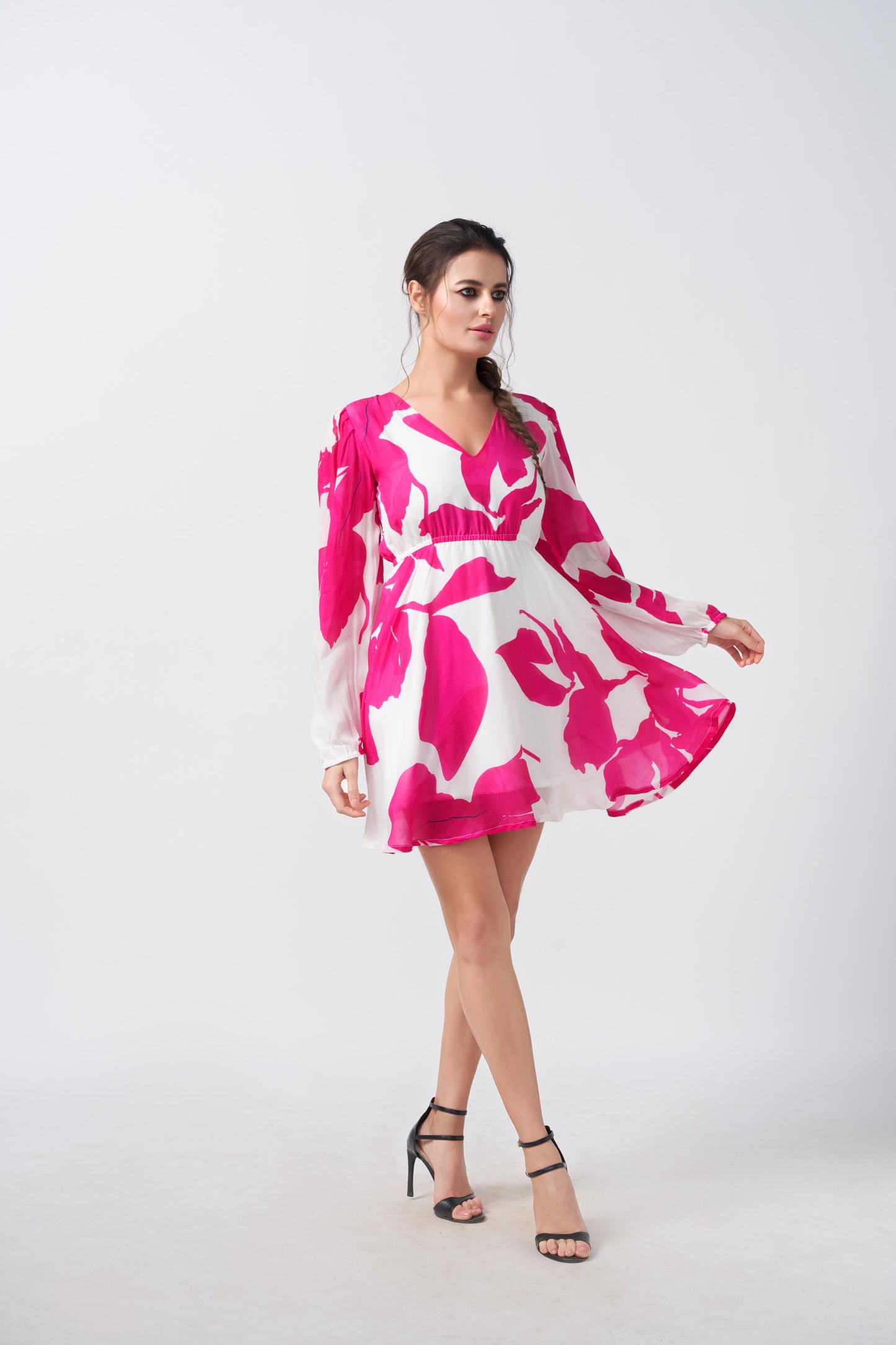 Walking pose of the model in pink and white V-neck dress, capturing the playful movement of the sleeves.