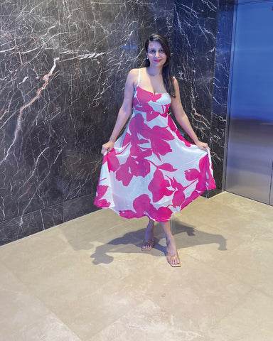 Midi-length dress featuring a vibrant hot pink floral print on a crisp white background, showcased in a lifestyle setting.