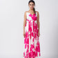 Model facing front in a pink and white floral ankle-length dress with spaghetti straps and gathered flare.