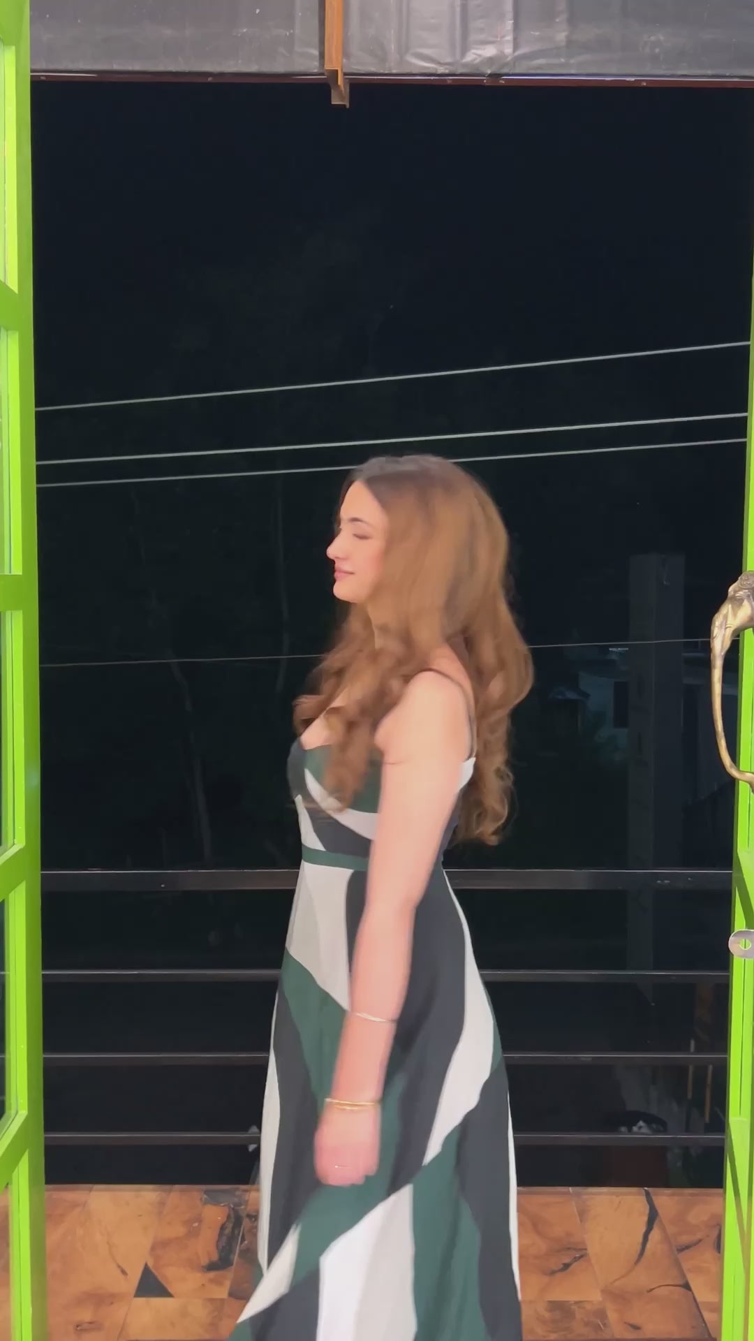 Video of the model in the abstract print midi dress walking outdoors at night.