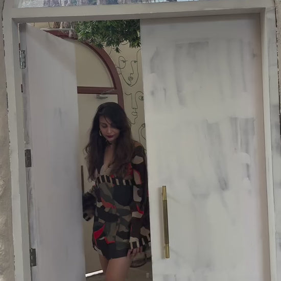 Model walking in boho-inspired chinon mini dress with deep V-neck, billowing sleeves, and multicolor abstract print