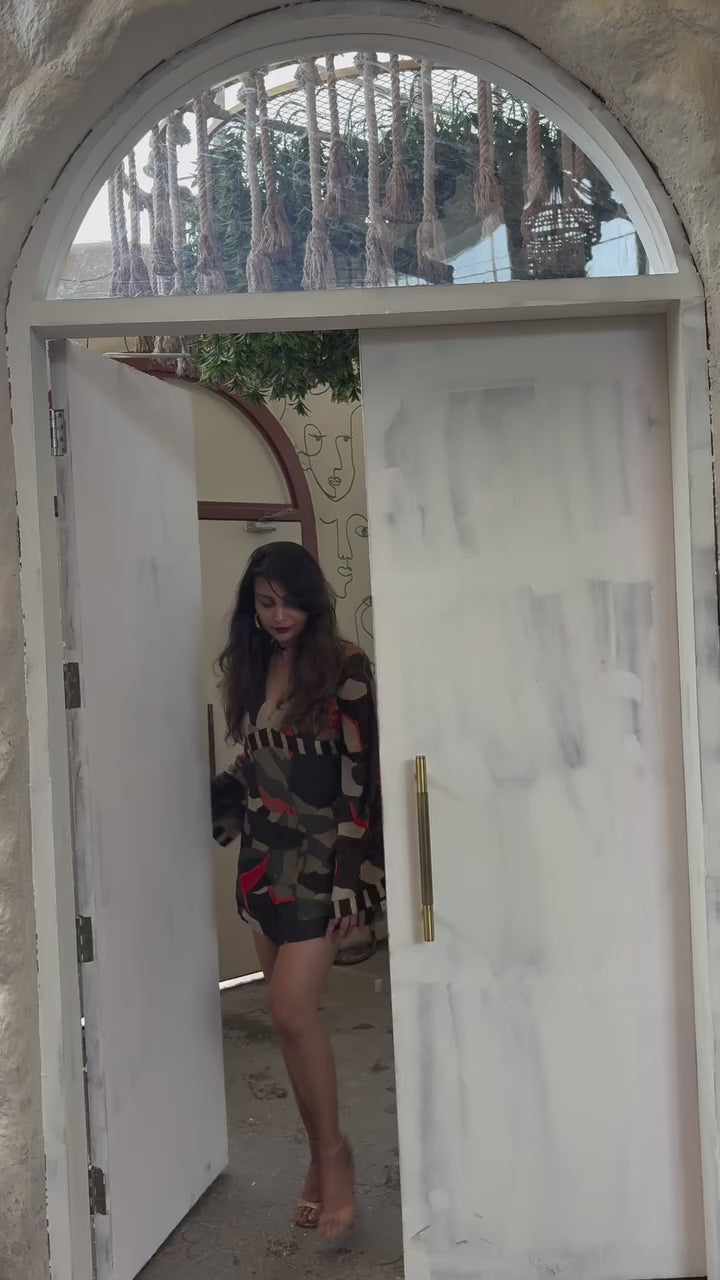 Model walking in boho-inspired chinon mini dress with deep V-neck, billowing sleeves, and multicolor abstract print