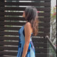 video of a model in halter neck blue floral crepe dress, highlighting the tie-back detail and flowy fabric.