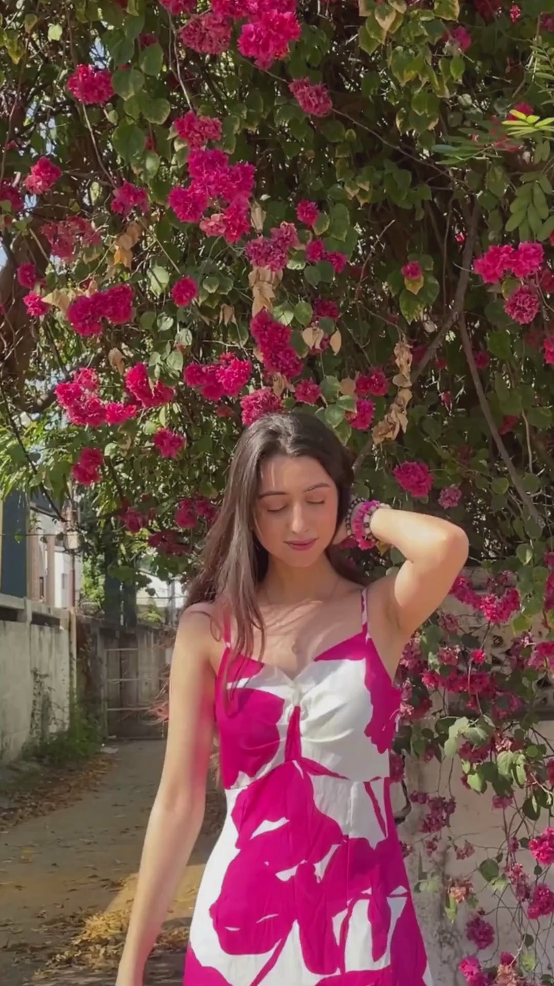 Video of a model outdoors near bougainvillaea, showcasing the vibrant print and flow of the gathered flare.