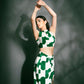 Model standing tall with both hands raised, showcasing the back tie-up and bold green abstract print of the summer co-ord set.