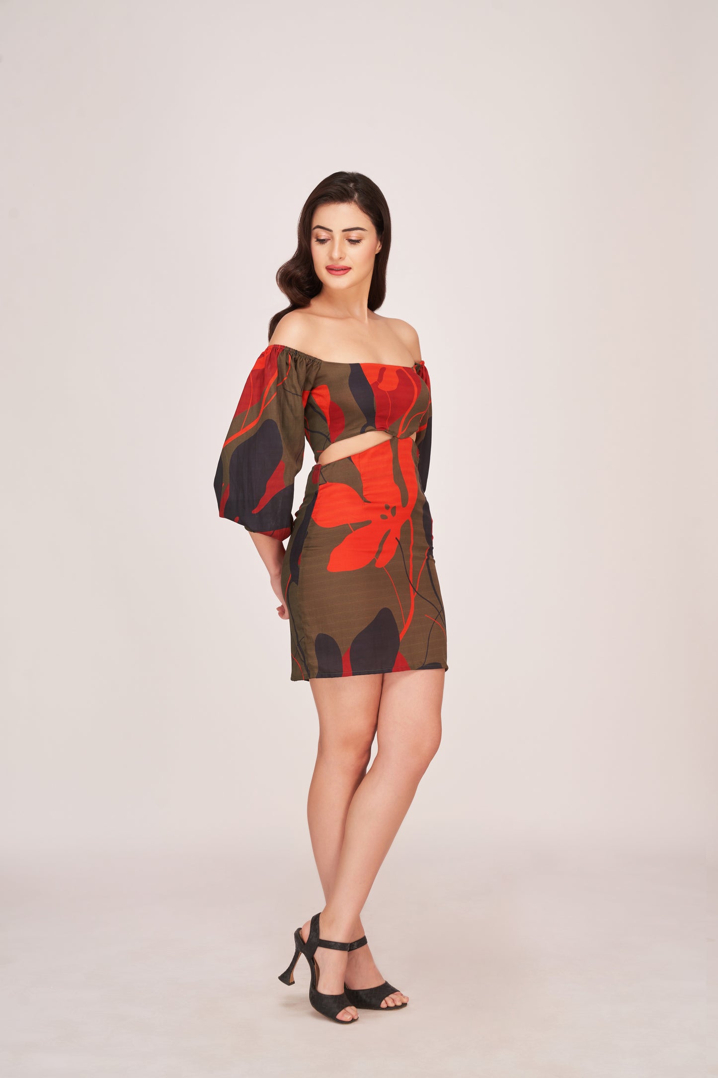 Model stands cross legged in off-shoulder floral satin mini dress with puffed sleeves and a confident expression.