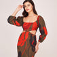 Model posing with hand on forehead in printed satin mini dress featuring full puff sleeves and bold floral pattern.