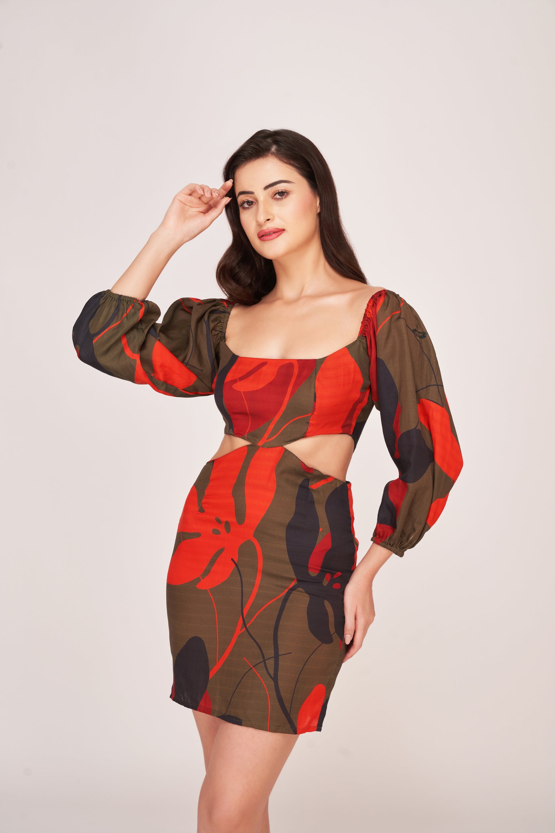 Model posing with hand on forehead in printed satin mini dress featuring full puff sleeves and bold floral pattern.