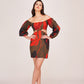 Model wearing a puff long sleeve satin mini dress with green base and red-black floral print, posing front-facing with hands on hips.