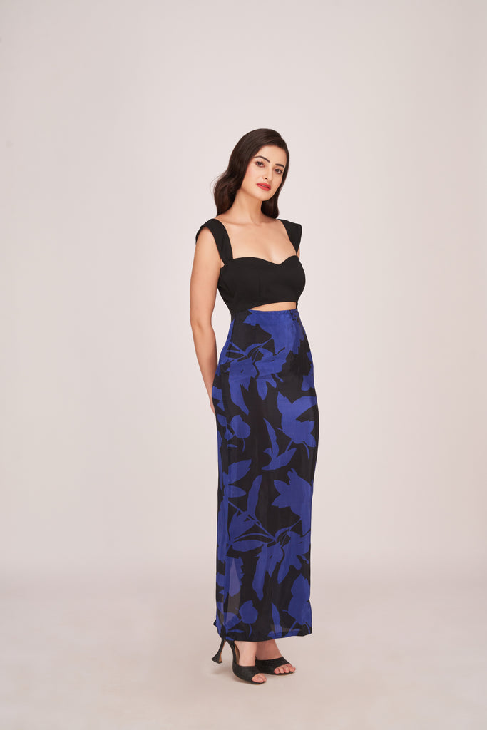 Model in a purple and black floral printed ankle-length dress with sweetheart neckline and strap shoulders, standing with arms relaxed.