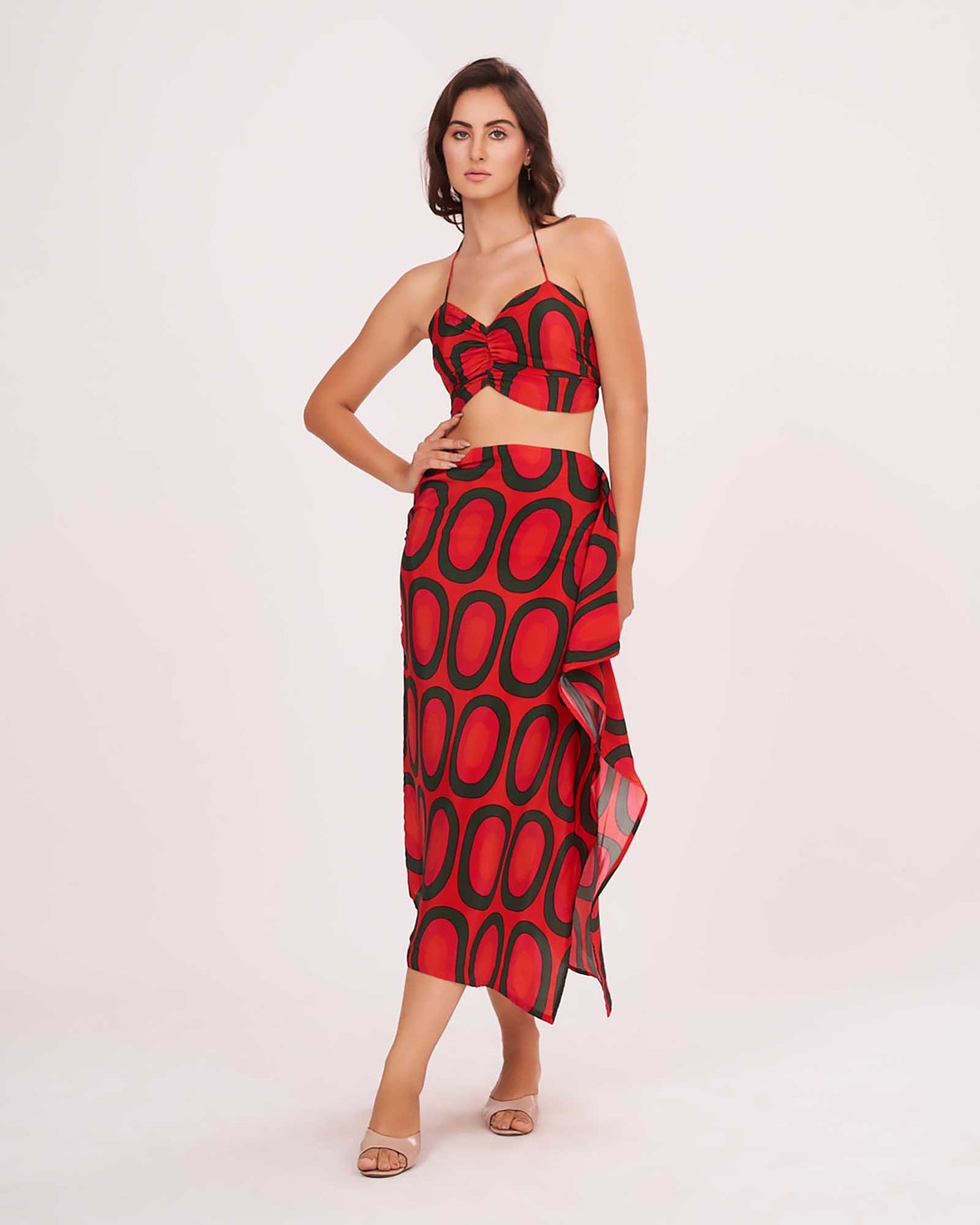 Model standing front-facing with hands on waist, wearing red printed crop top and abstract frill skirt.