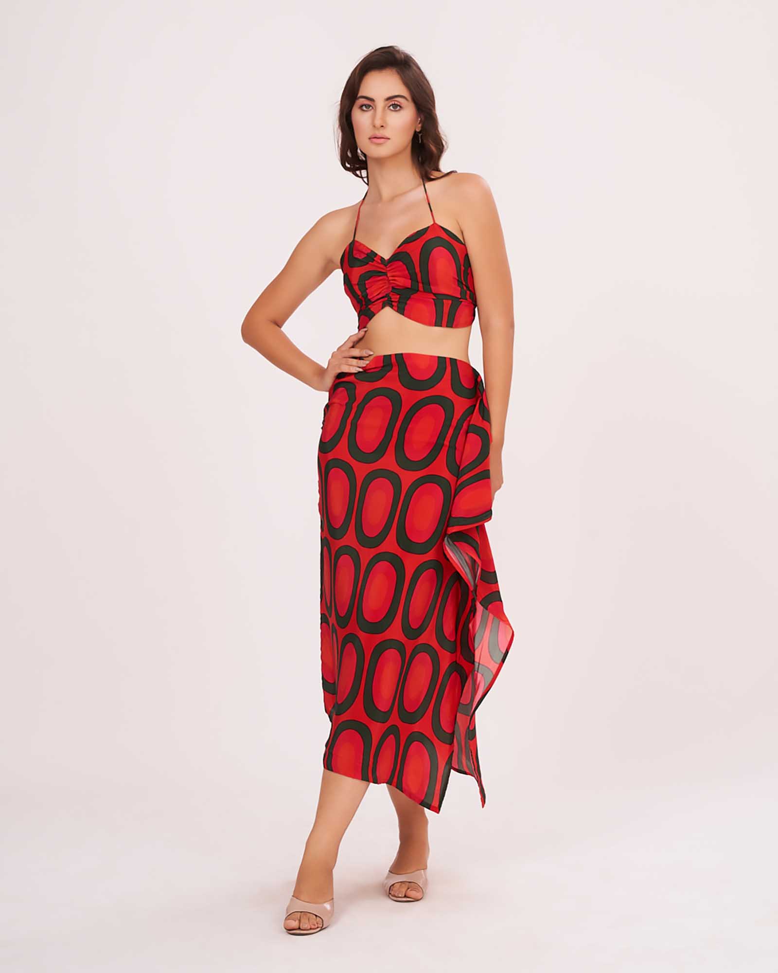 Model standing front-facing with hands on waist, wearing red printed crop top and abstract frill skirt.