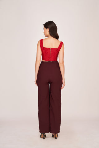 Back view of a red corset top with a back zip closure paired with brown trousers