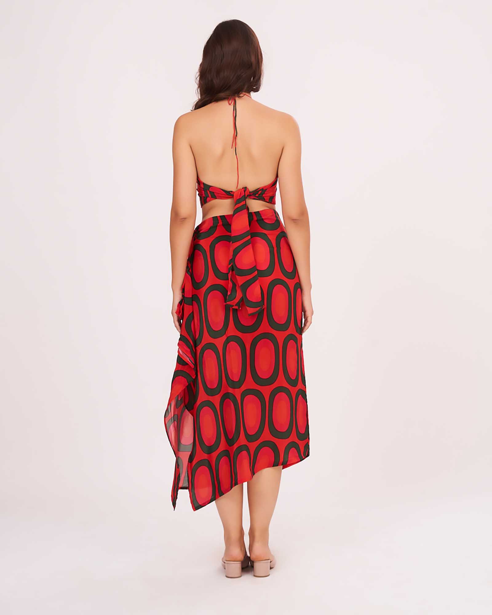 Rear view showing the open tie-back red crop top and the cascading frill detail of the abstract skirt.