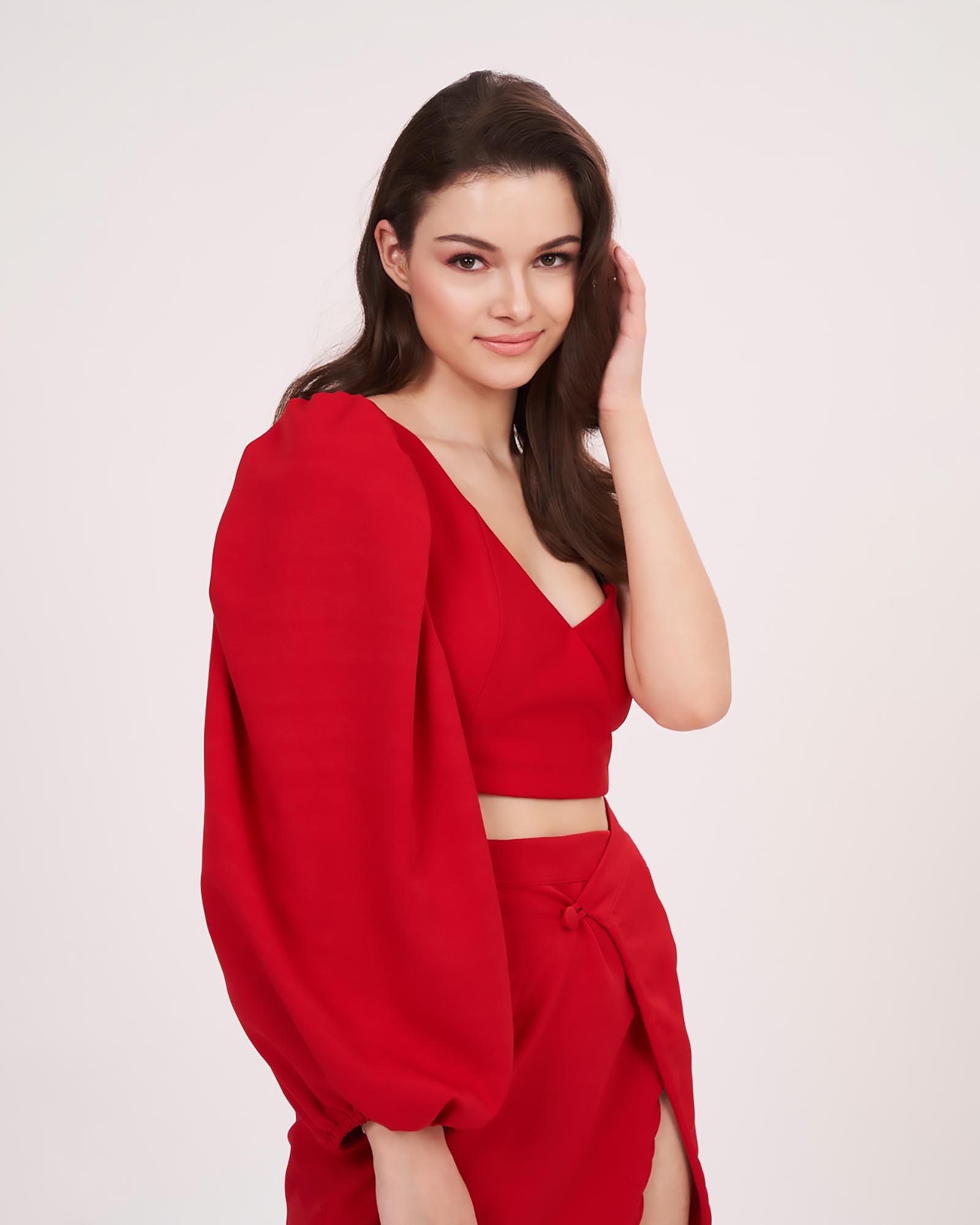 Side view of model turning slightly with one arm relaxed, showing the drape and flow of the mini skirt and the structured cut of the single sleeve top.