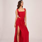 Model in motion in red velvet corset top and ankle-length skirt, highlighting pleats and movement of the high-slit design.