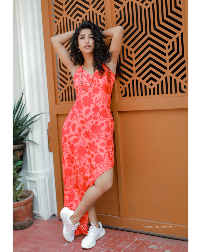 Red floral high-low dress with spaghetti straps, model posing outdoors with hand in hair.