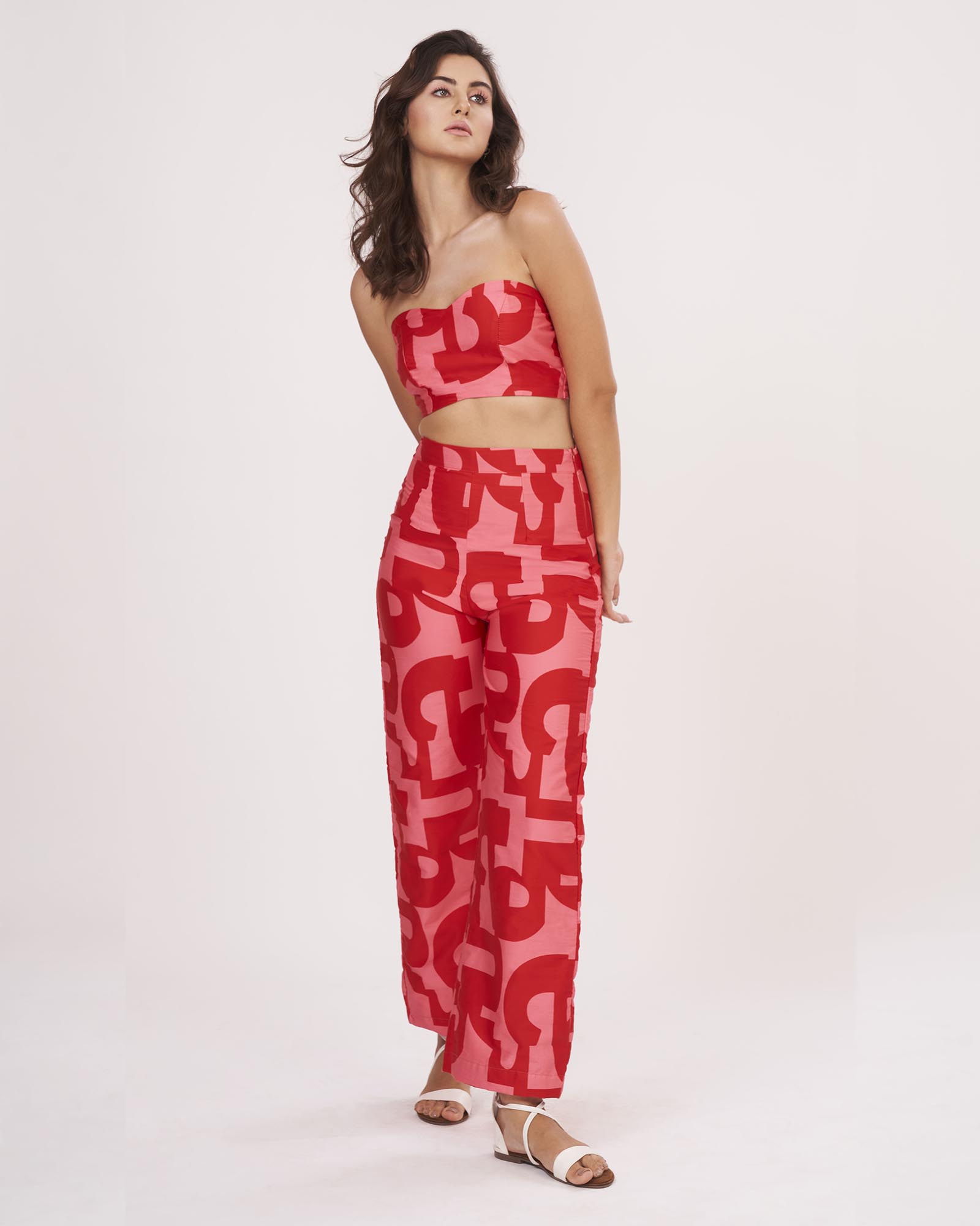 Model wearing red geometric printed co-ord set with tube crop top and wide-leg palazzo pants, standing front-facing in a relaxed pose.
