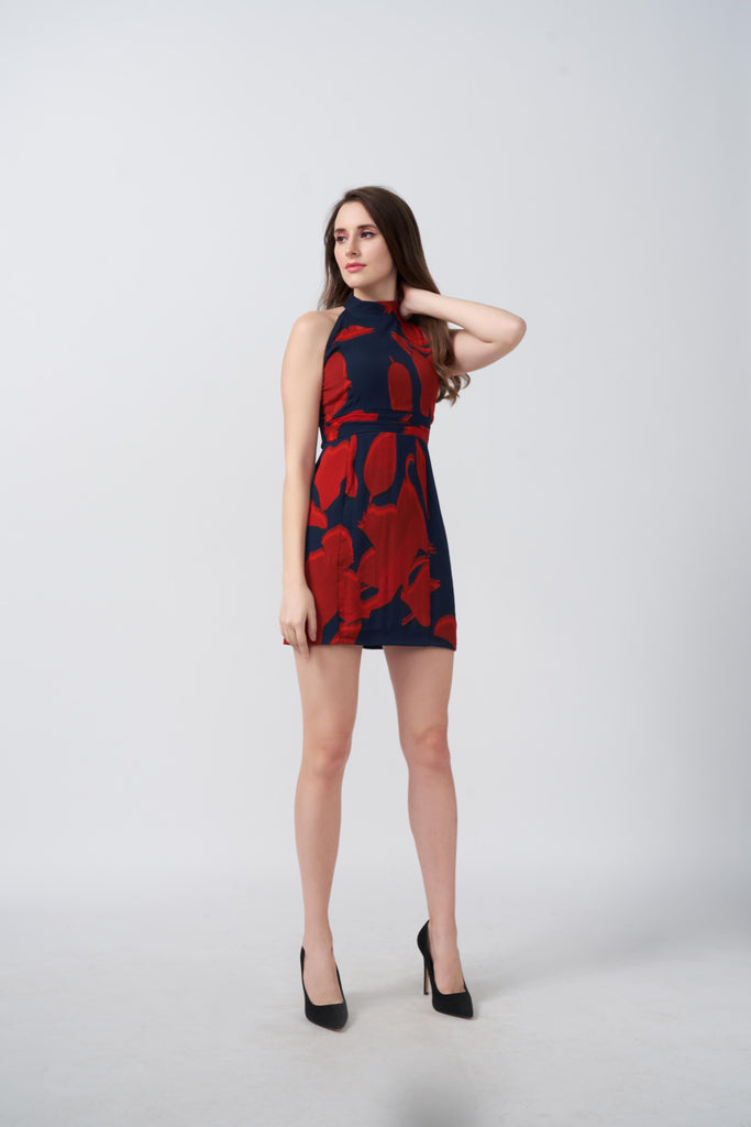 Model standing confidently in a red and navy abstract floral halter dress, showcasing the sleek silhouette.