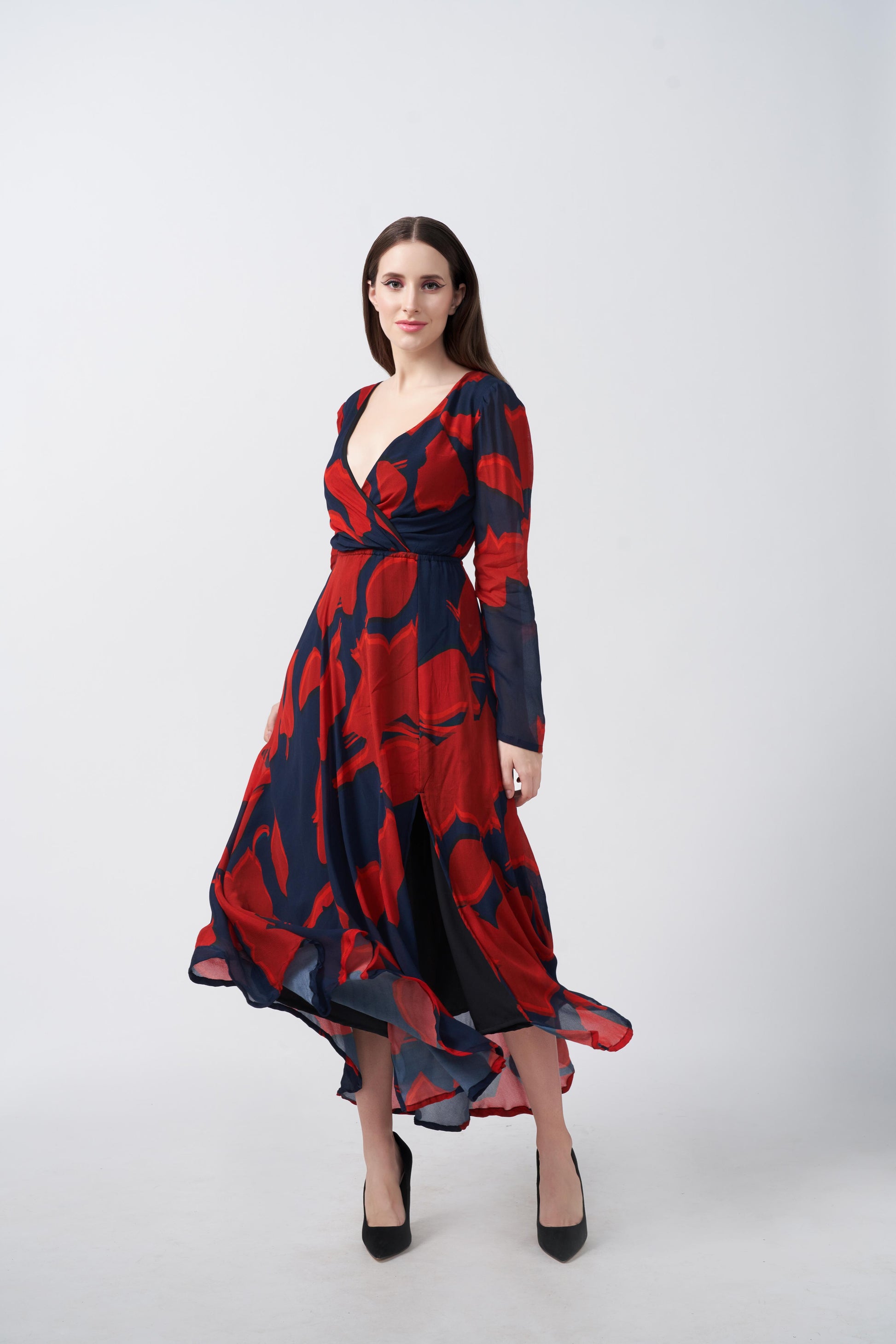 Full-length walking pose of model showcasing flow and slit of red and navy abstract dress.